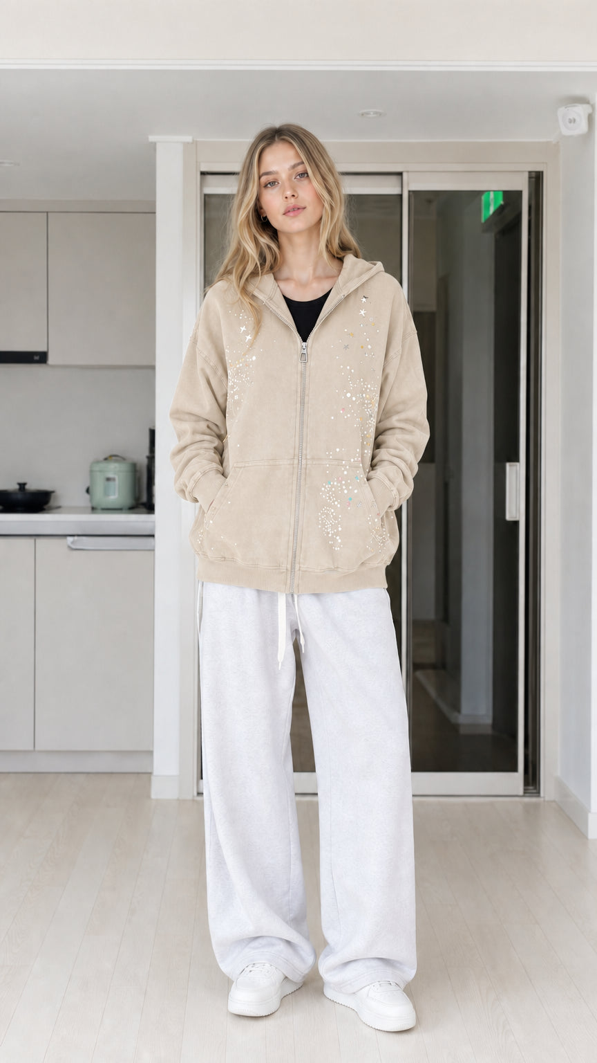 Front view of woman wearing beige rhinestone star zip-up hoodie