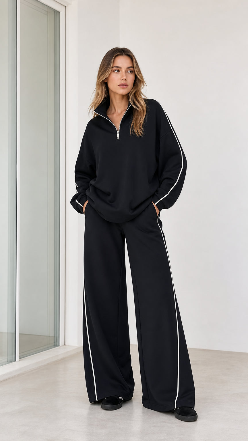 Front full-body view of model wearing black half zip sweatshirt and wide leg pants 2-piece set with white piping