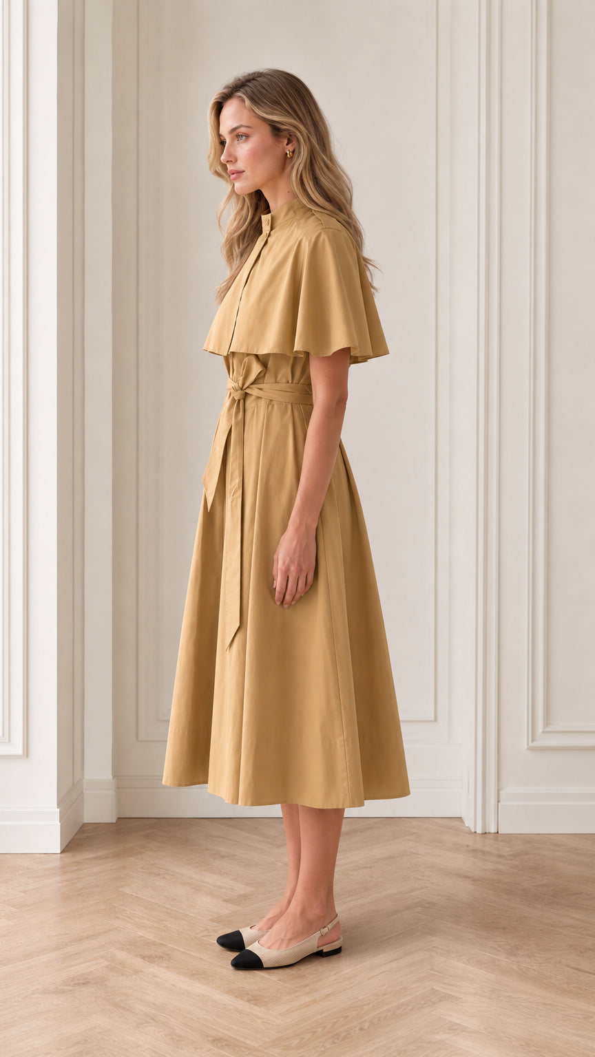 Side profile of model in camel capelet midi dress with belted waist