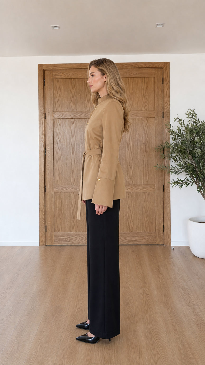 Side profile view of model in camel stand collar belted jacket
