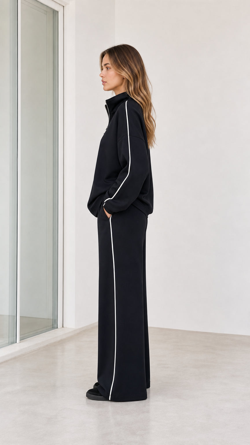 Side profile view of model wearing black 2-piece wide leg tracksuit set
