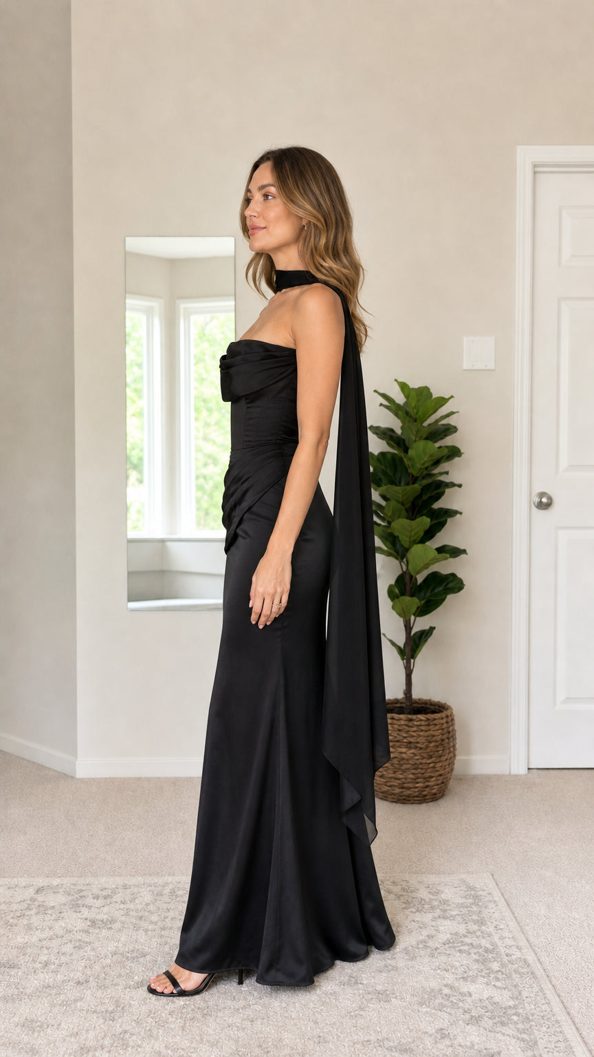 Side profile of black strapless satin evening dress with long trailing scarf