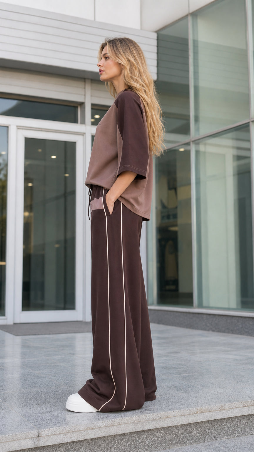 Side profile of women's mocha brown two-piece wide-leg tracksuit set with side piping