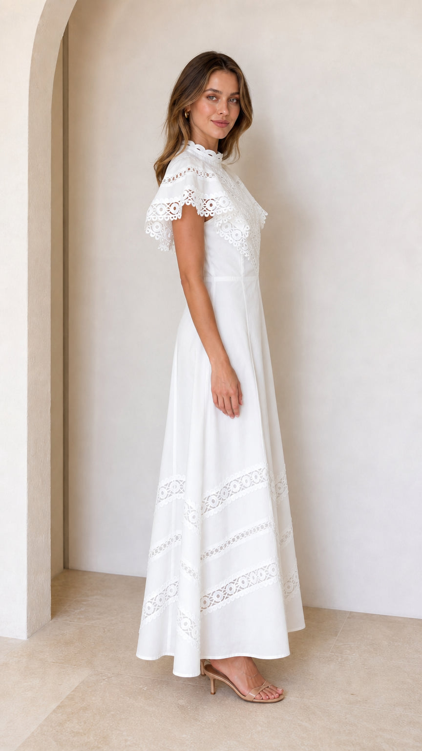 Side profile view of woman wearing white A-line lace maxi dress