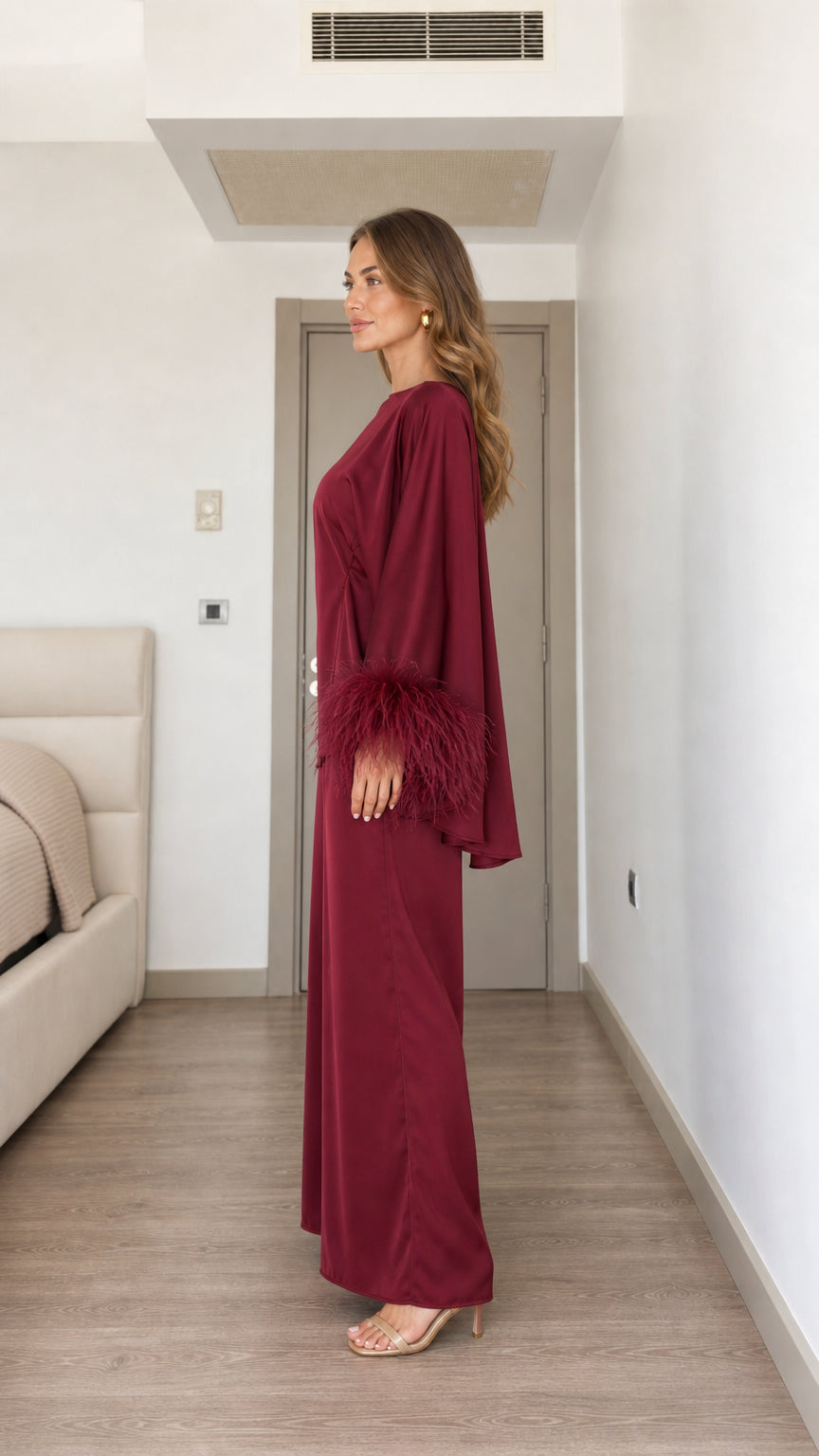 Side profile of woman in burgundy feather cuff top and wide-leg trousers