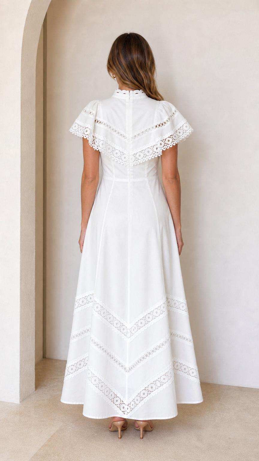 Back view of white lace maxi dress showing flutter sleeves and skirt hem