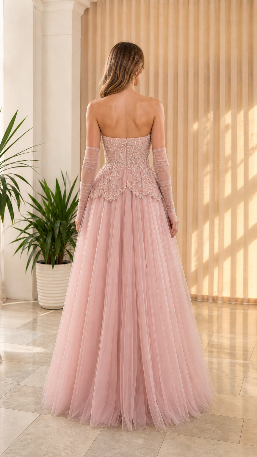 Back view of dusty pink strapless formal evening dress showcasing fitted corset back and tulle skirt