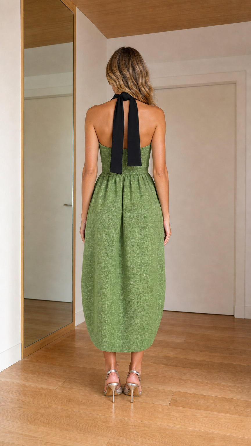 Back view of woman wearing sage green halter dress with black tie sash