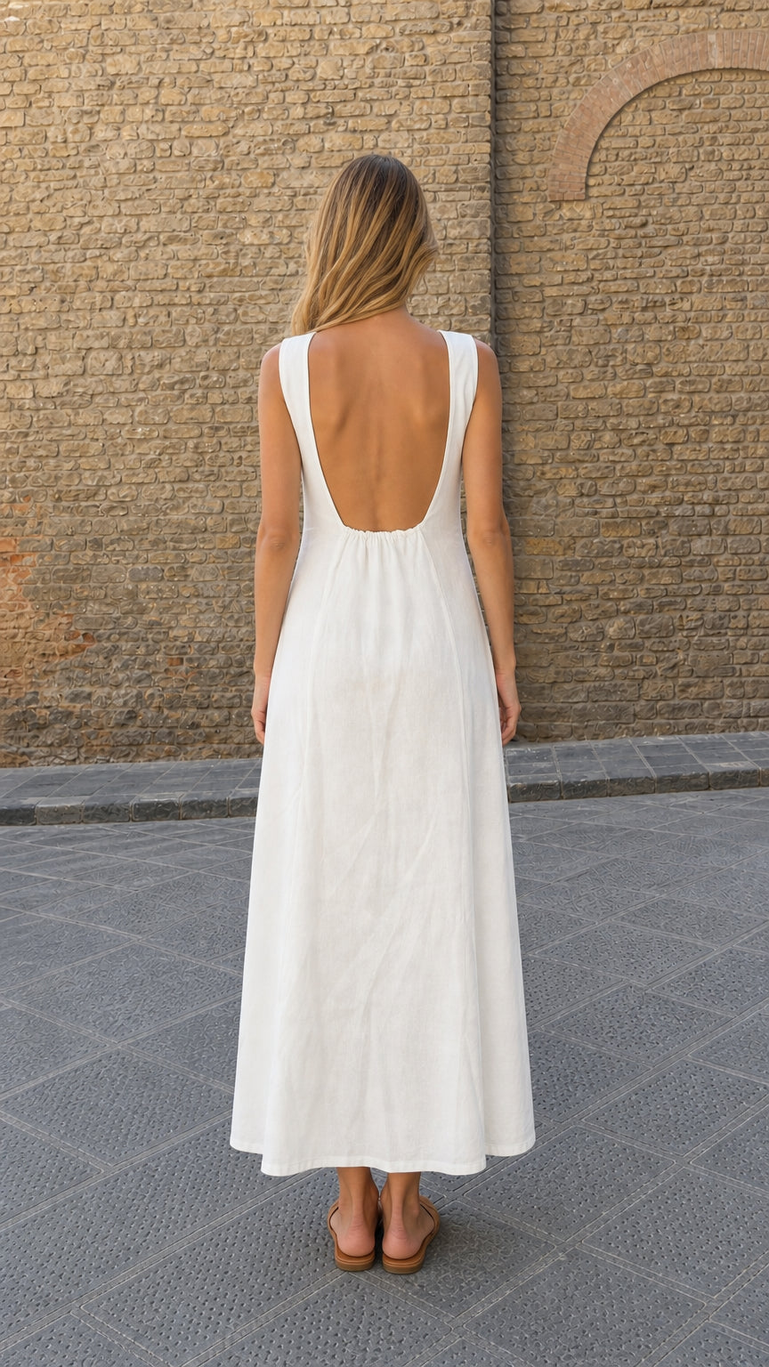 Back view of model showing the low scoop back design of white linen maxi dress
