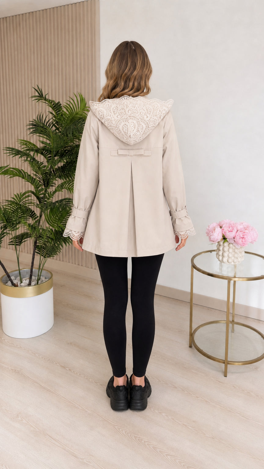 Back view of beige hooded coat showing lace hood trim and back bow pleat