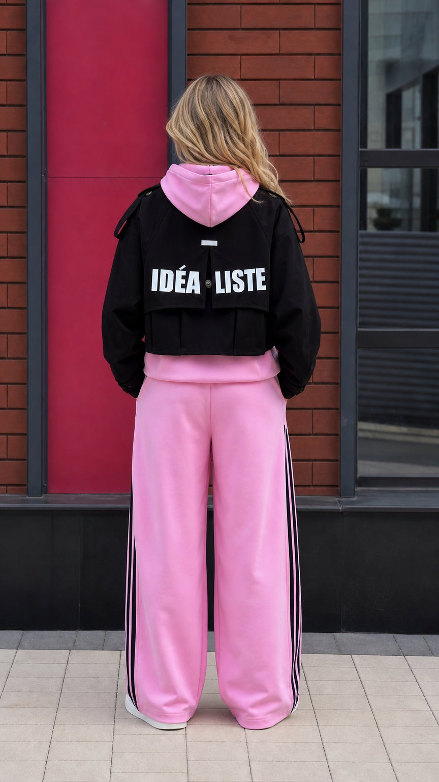 Back view of black cropped jacket featuring IDEALISTE lettering over pink hoodie and pants