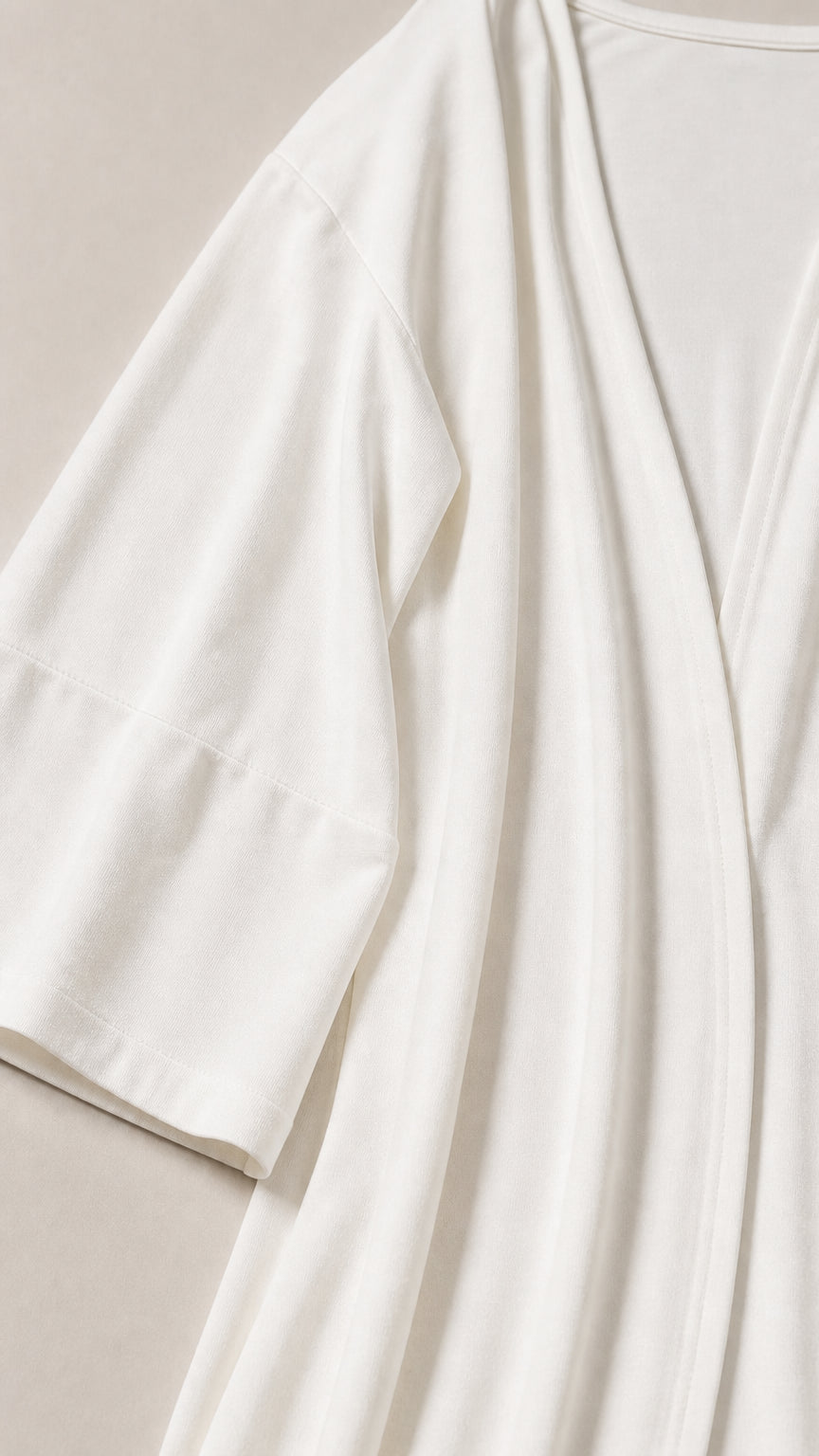 Close-up of smooth, lightweight white jersey fabric on cardigan and top