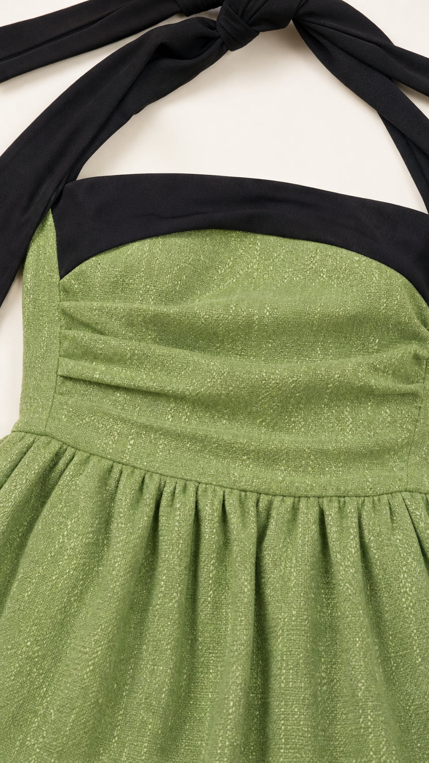 Close-up detail of textured sage green fabric and pleated bodice with black halter