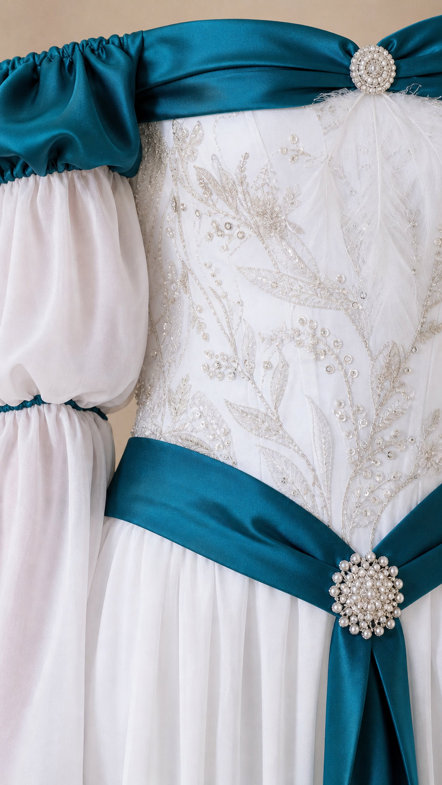 Close-up detail of embroidered floral bodice and crystal brooch on white and teal gown