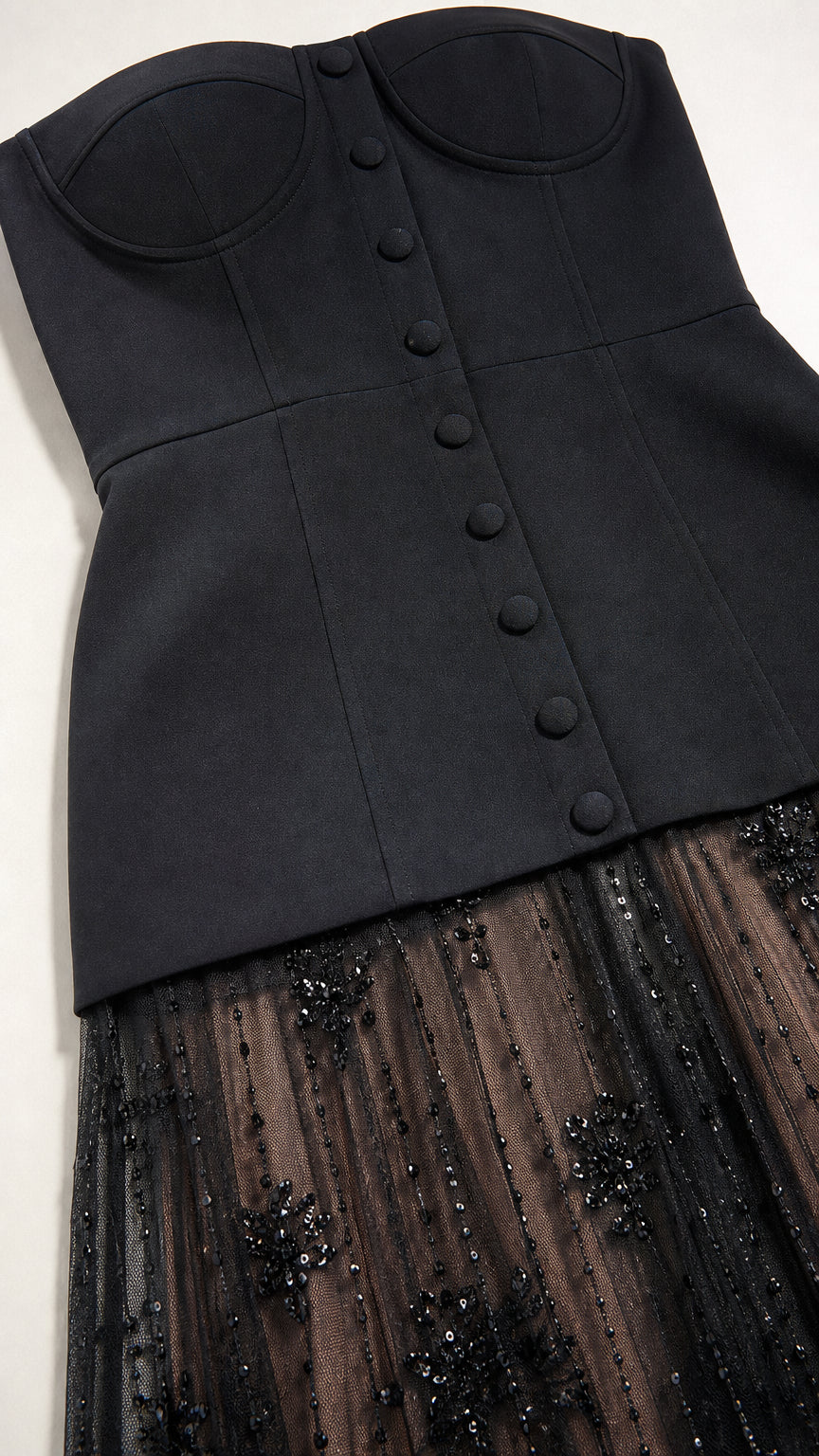 Close-up detail of structured black sweetheart bustier with covered buttons and sequined mesh