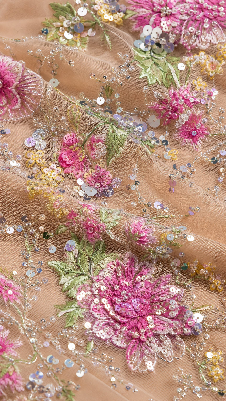Close-up detail of sheer mesh fabric with colorful floral embroidery and sparkling sequins