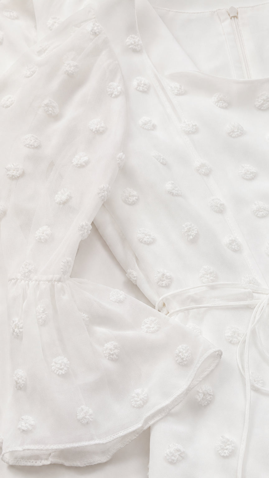 Close-up detail of white Swiss dot chiffon fabric and bell cuff sleeve