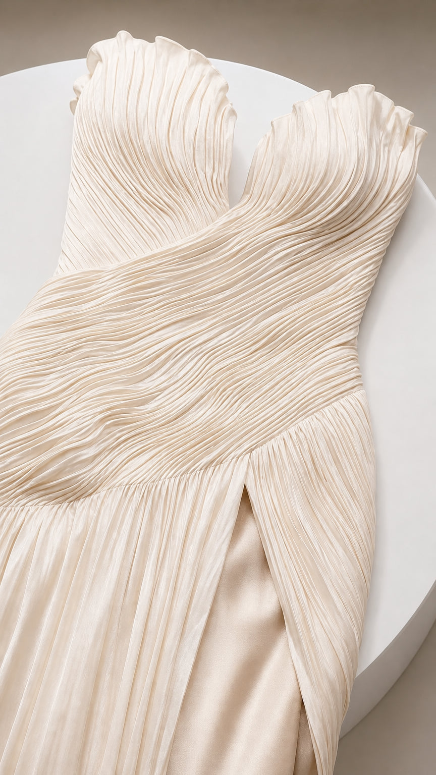 Close-up detail of sweetheart neckline, micro-pleating, and slit on champagne gown