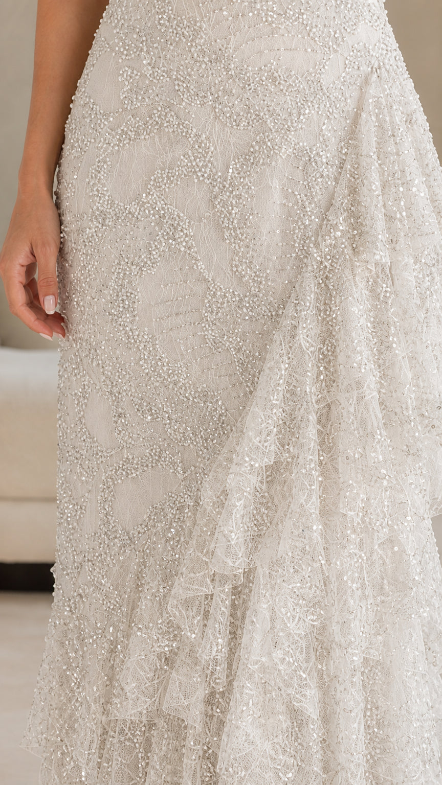 Close-up detail of textured fabric and side ruffle on ivory gown