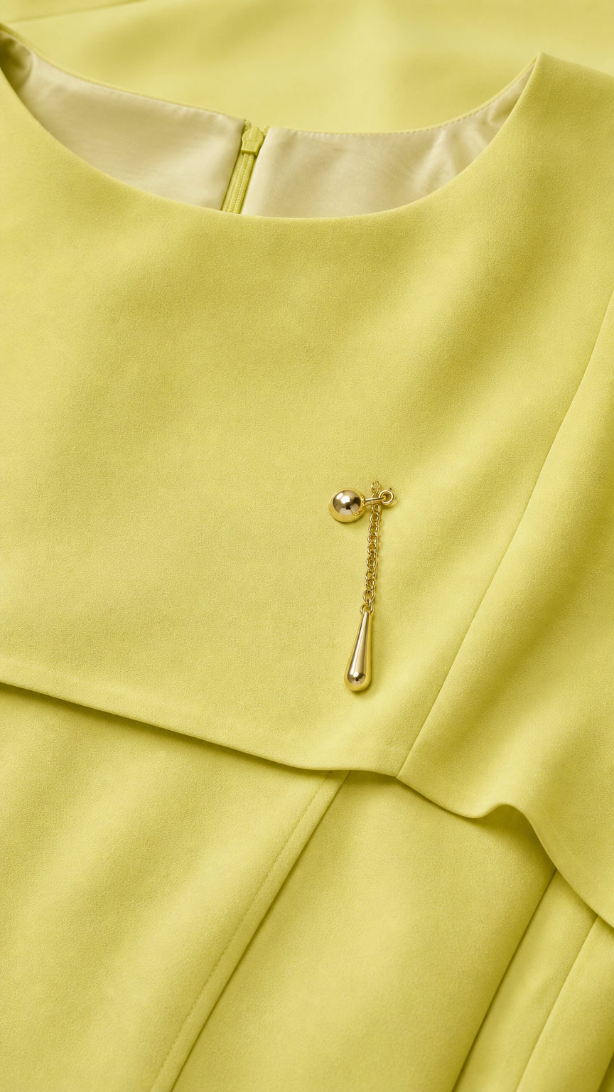 Close-up of boat neckline and gold brooch pin detail on yellow gown