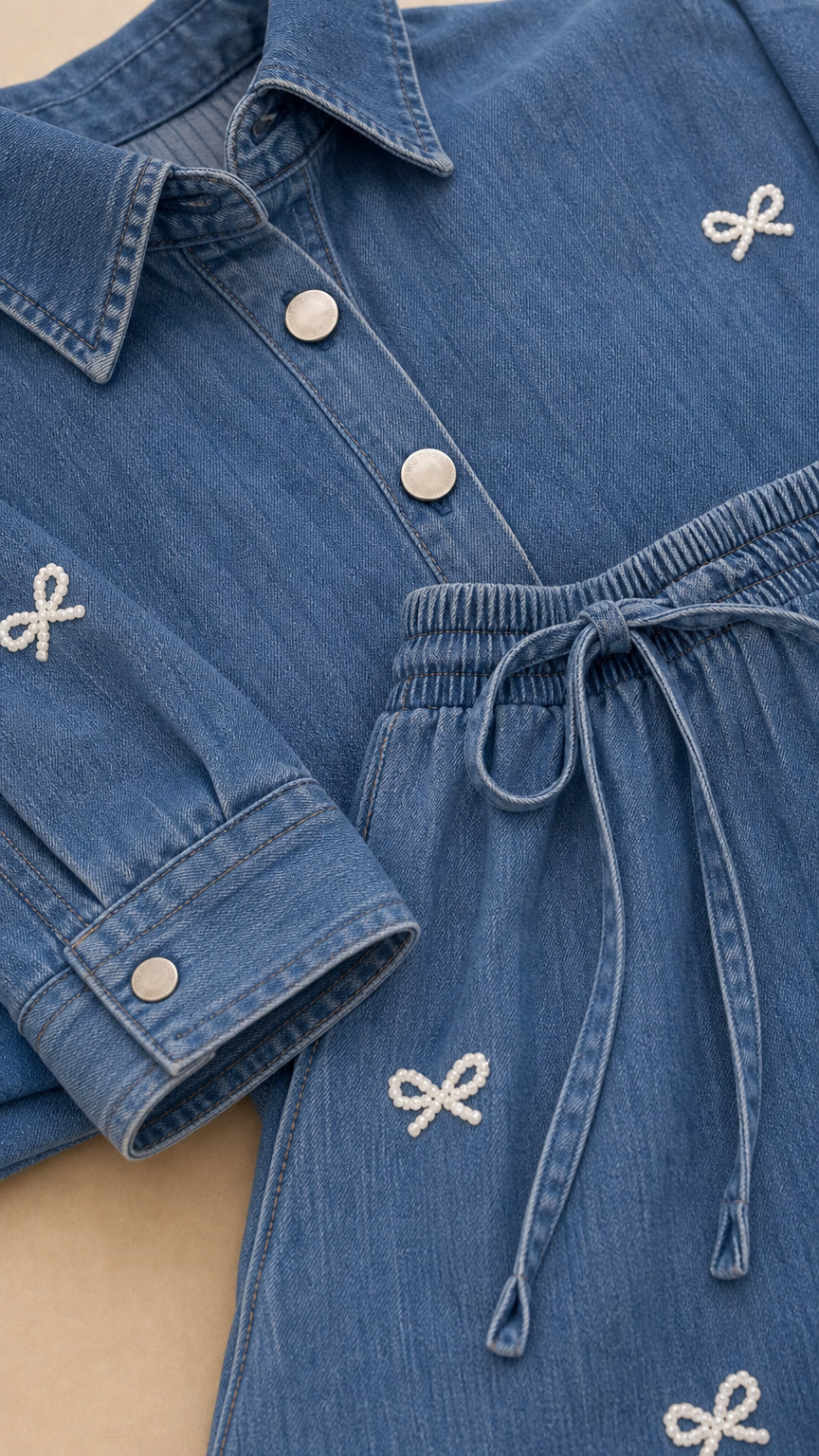 Close-up detail of blue denim shirt buttons and drawstring pants with bow embroidery