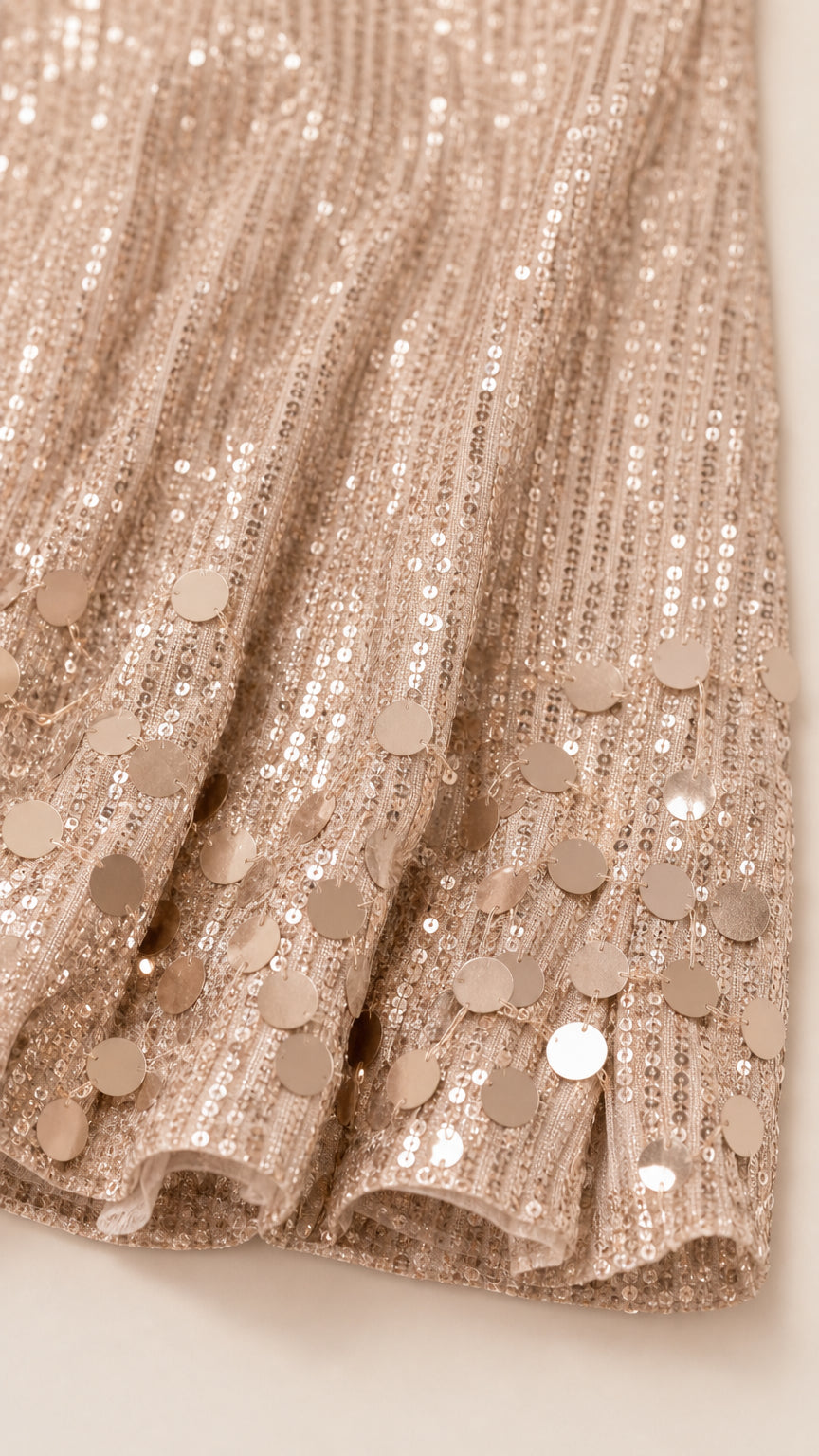 Close-up detail of champagne sequins and round paillette embellishments on hem