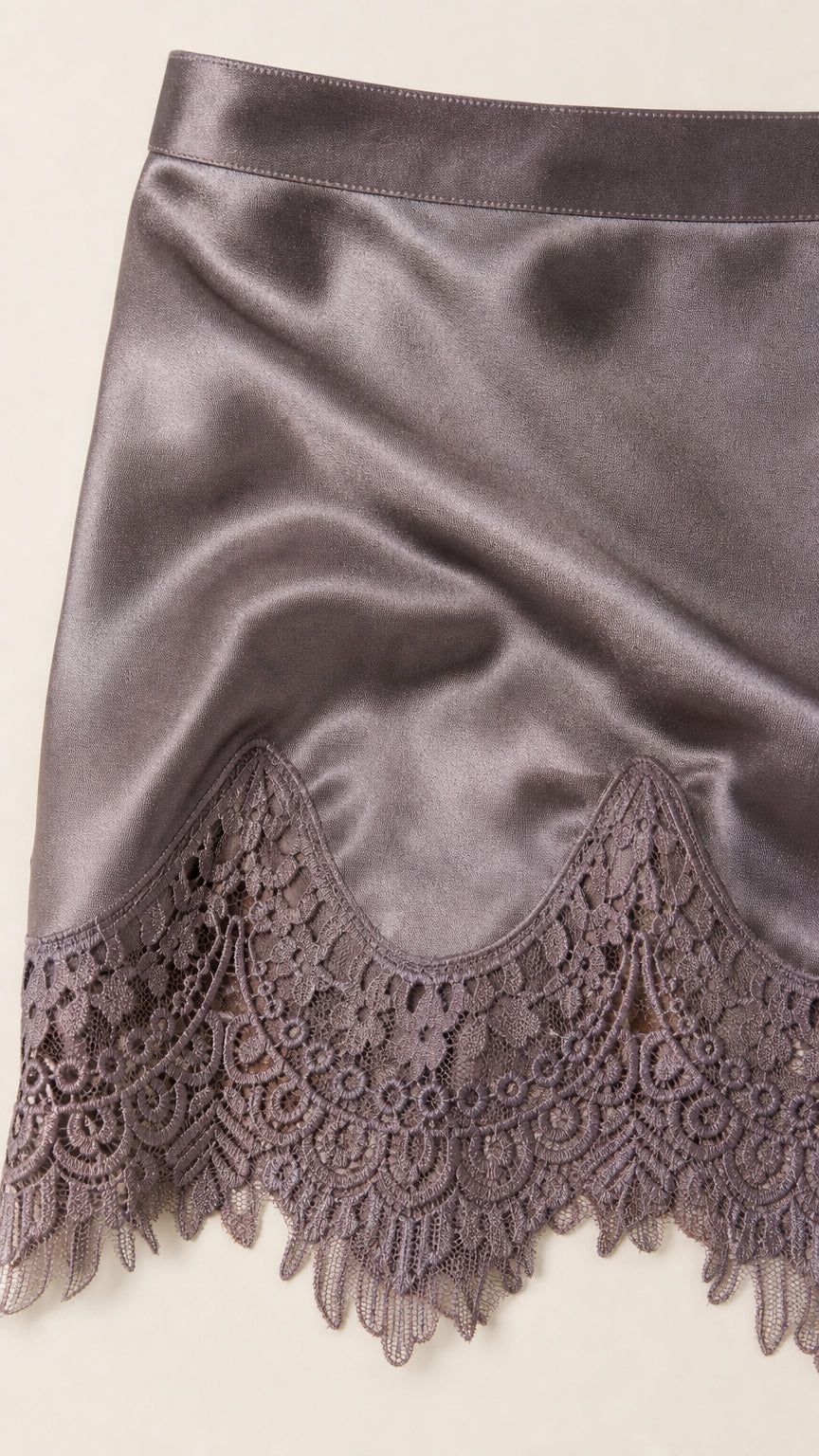 Close-up detail of smooth satin fabric and scalloped floral lace trim hemline