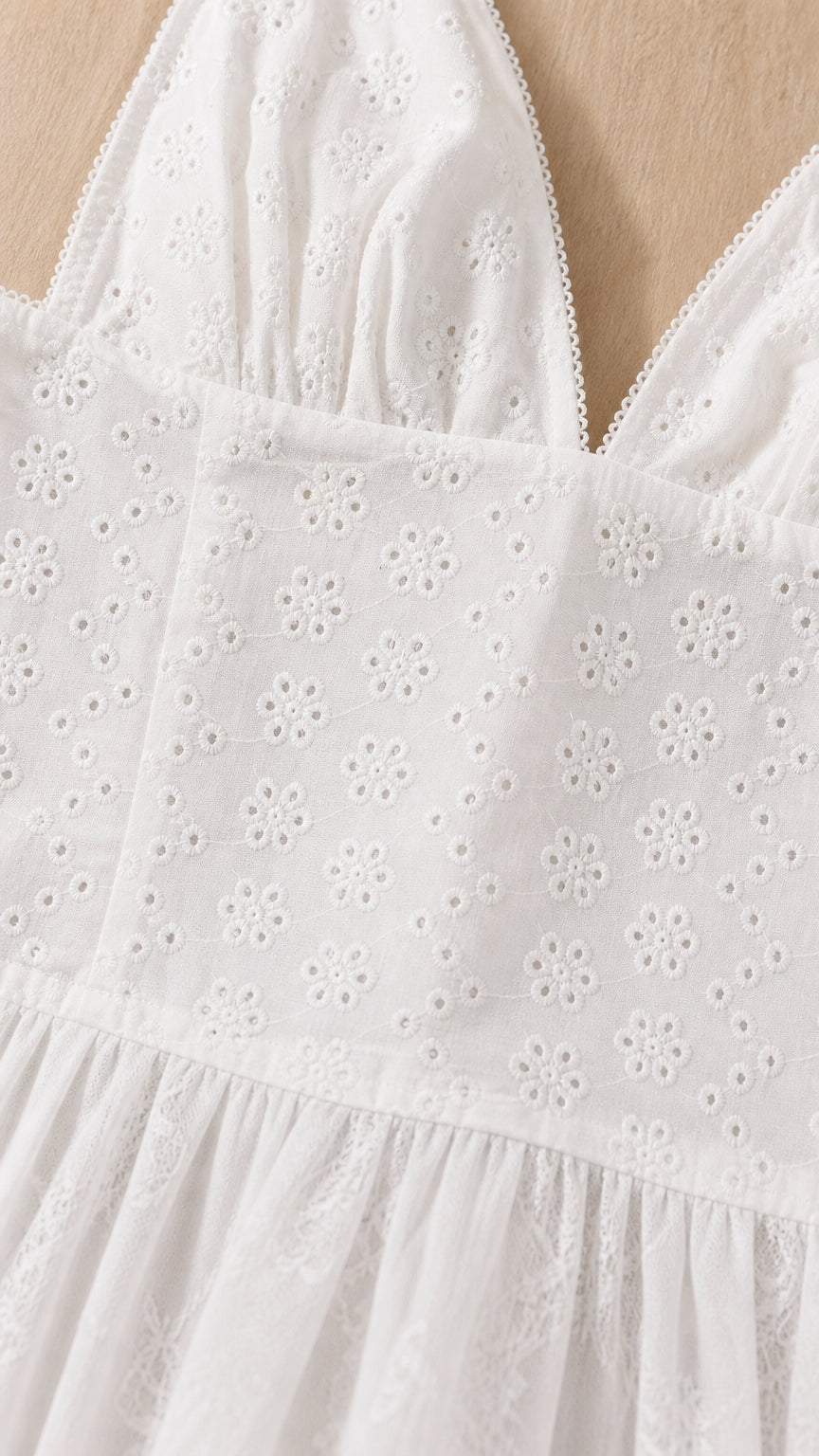 Close-up detail of white floral eyelet embroidery and bodice seams