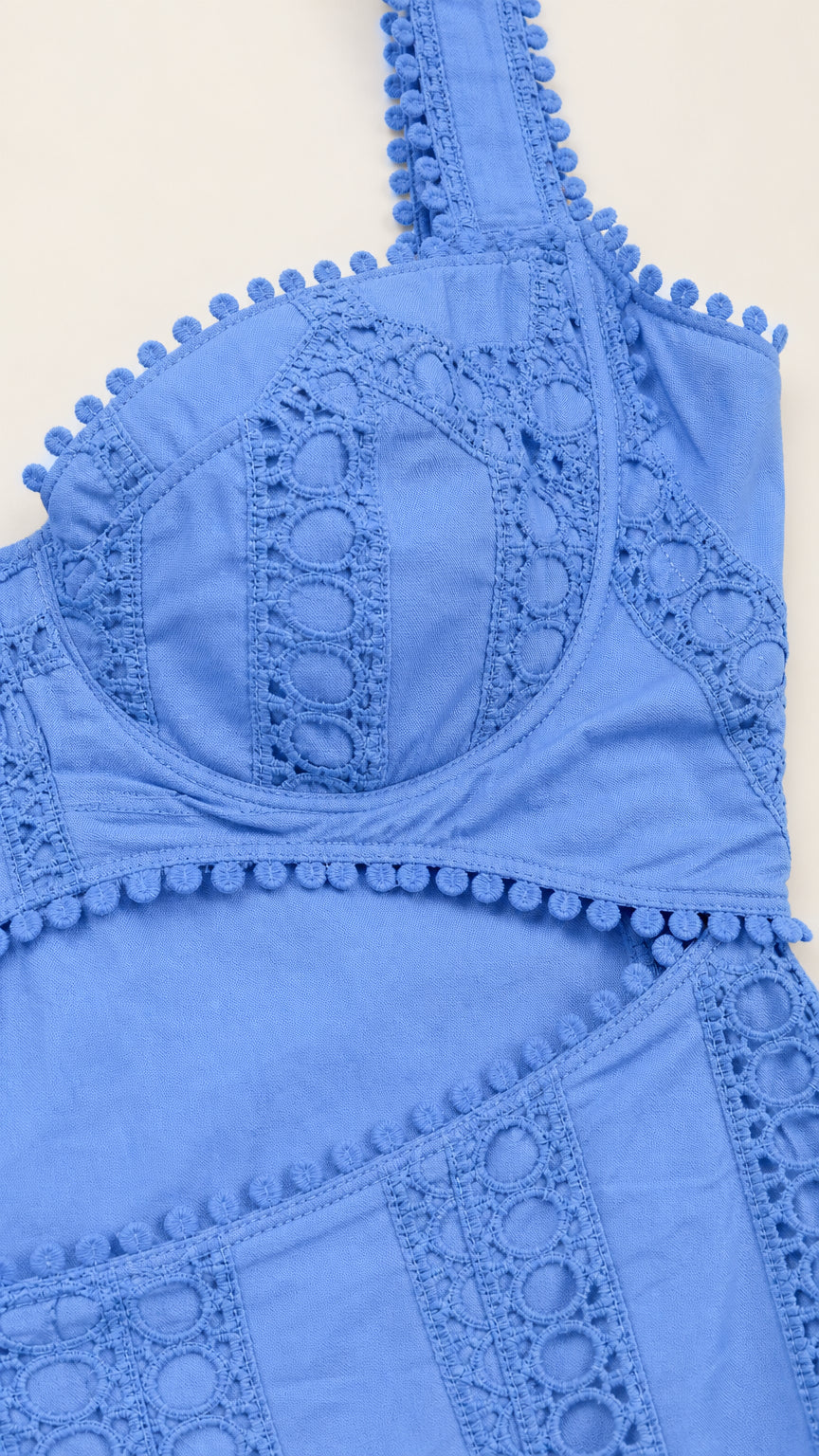 Close-up detail of blue bodice, pom-pom trim, and cutout