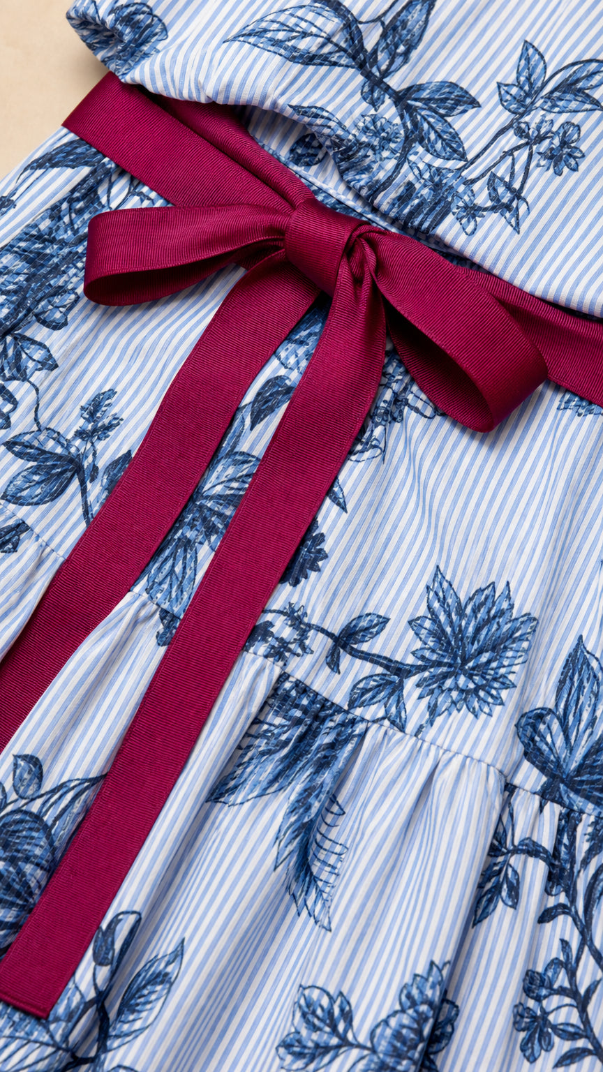 Close-up detail of blue striped floral fabric and contrast burgundy ribbon tie