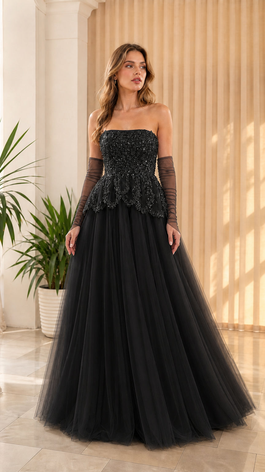 Full-length front view of black strapless beaded peplum tulle evening gown with sheer gloves