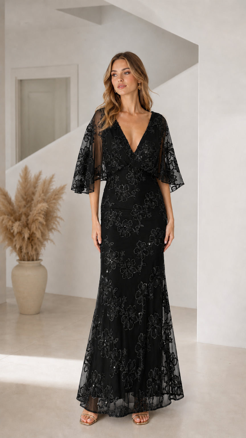 Front view of woman wearing black floral sequin flutter sleeve evening maxi dress