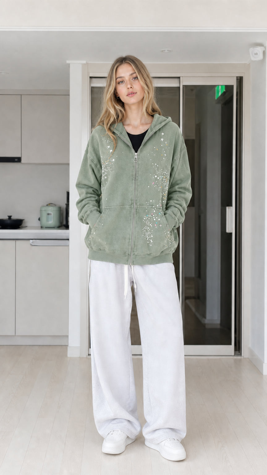 Front view of woman wearing sage green rhinestone star zip-up hoodie