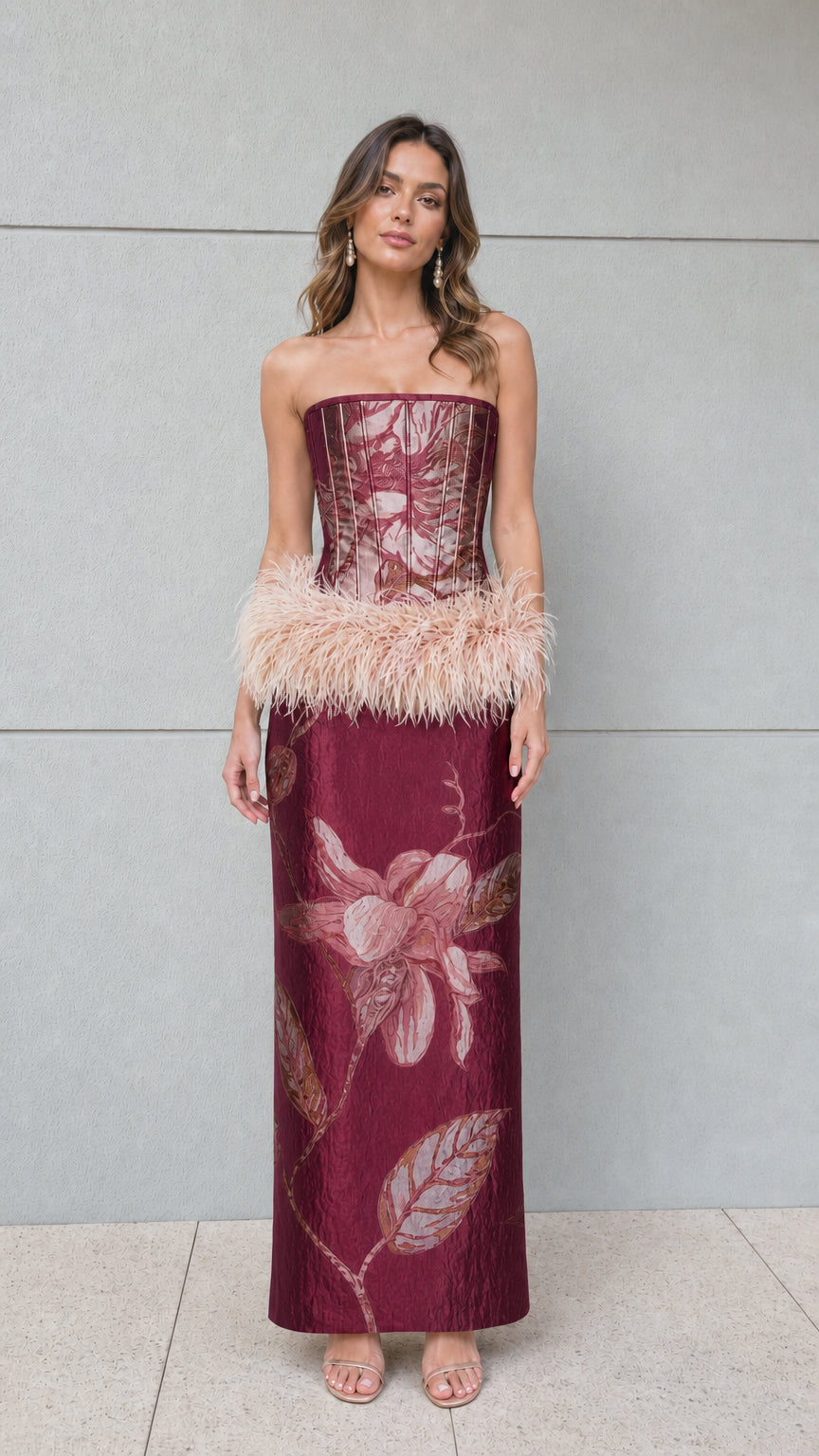 Front view of burgundy floral jacquard strapless corset maxi dress with blush feather trim