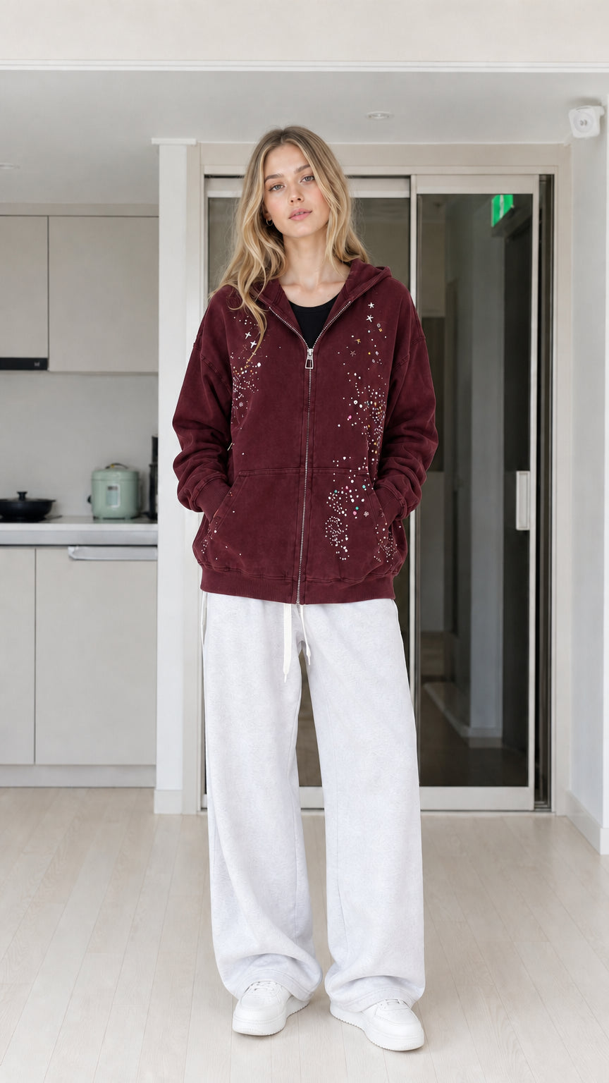 Front view of woman wearing burgundy rhinestone star zip-up hoodie