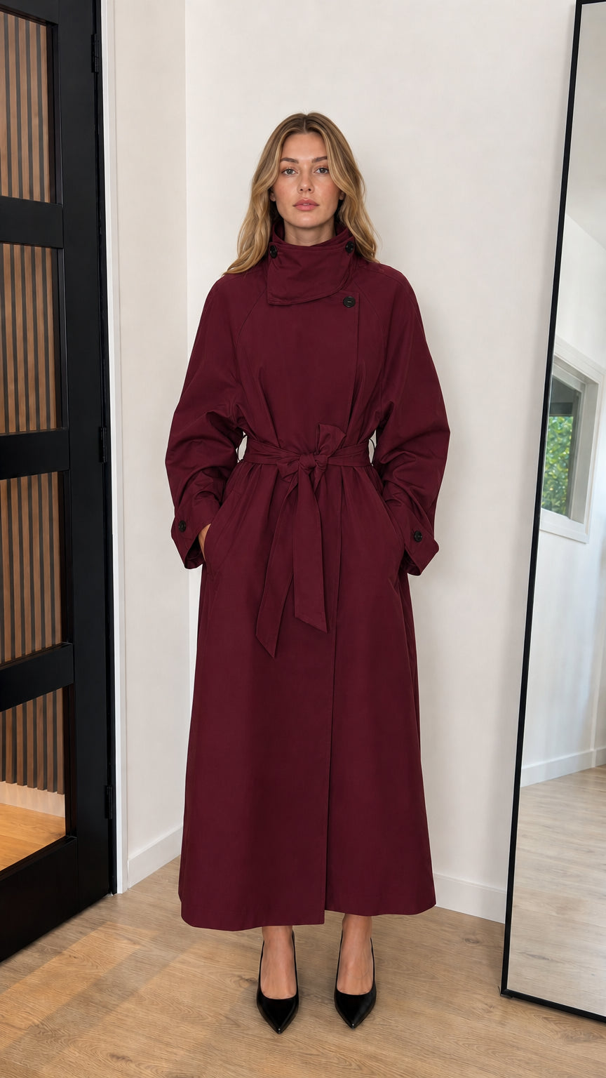 Front view of model wearing a burgundy wine red high neck belted longline trench coat